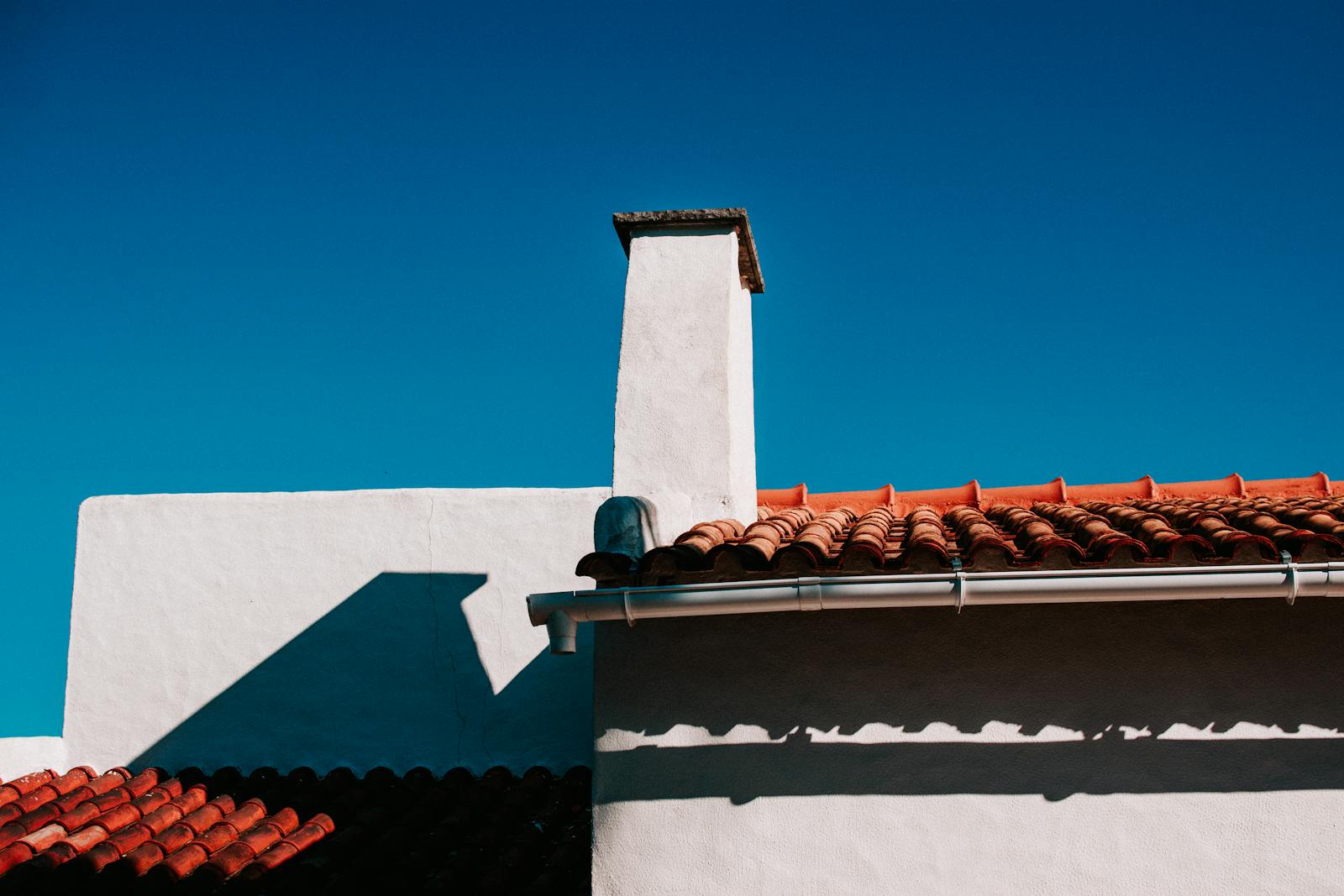 Low angle view of a traditional terracotta rooftop under a clear blue sky in summer.